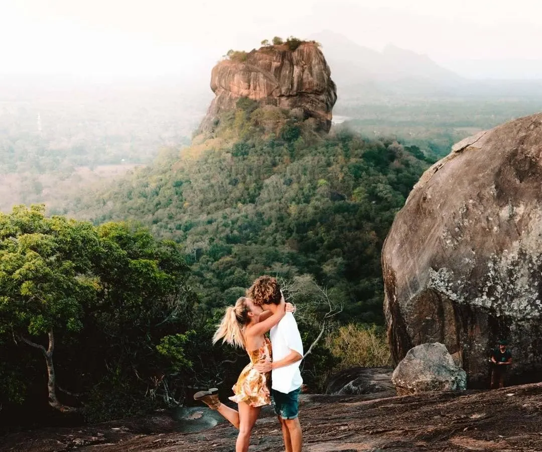 A couple embracing on Pidurangala Rock with Sigiriya rising behind
