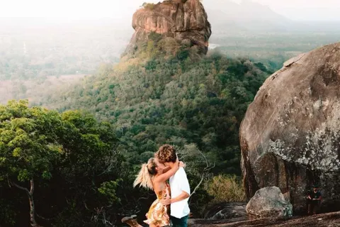 A couple embracing on Pidurangala Rock with Sigiriya rising behind