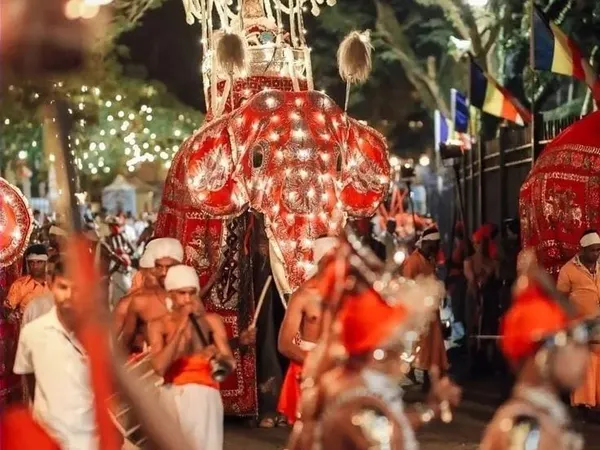 A ceremonial elephant in lights leading drummers through the Kandy Esala Perahera