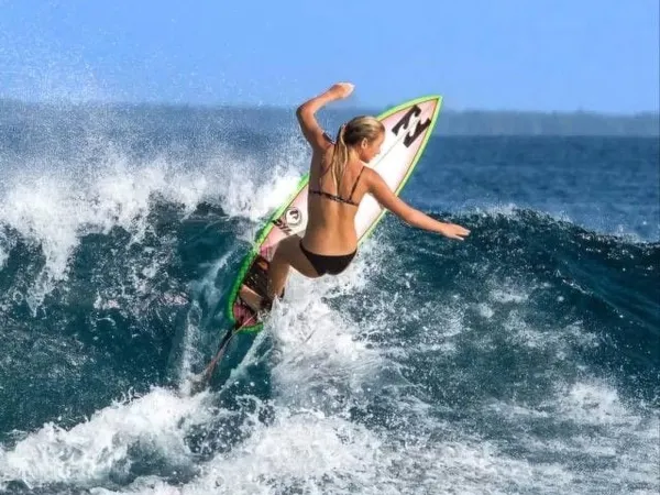 A surfer carving across a breaking wave