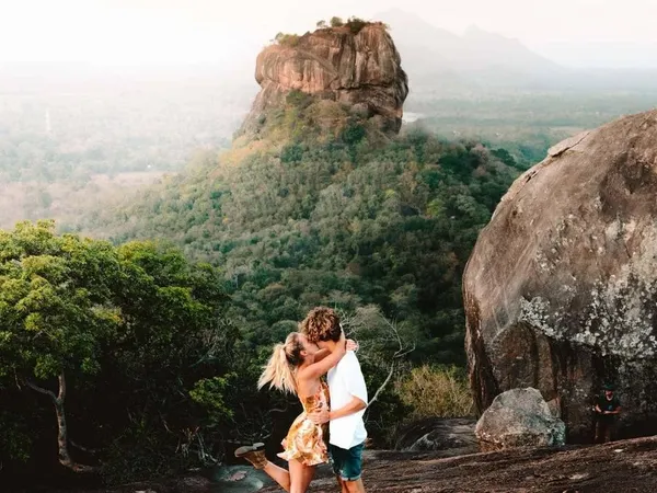 A couple embracing on Pidurangala Rock with Sigiriya rising behind
