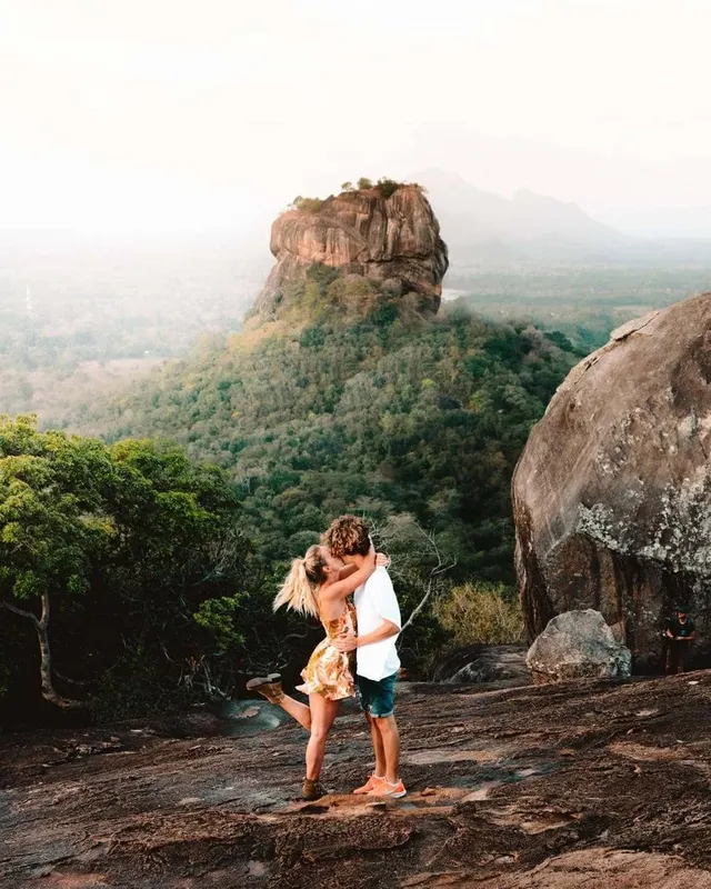 A couple embracing on Pidurangala Rock with Sigiriya rising behind